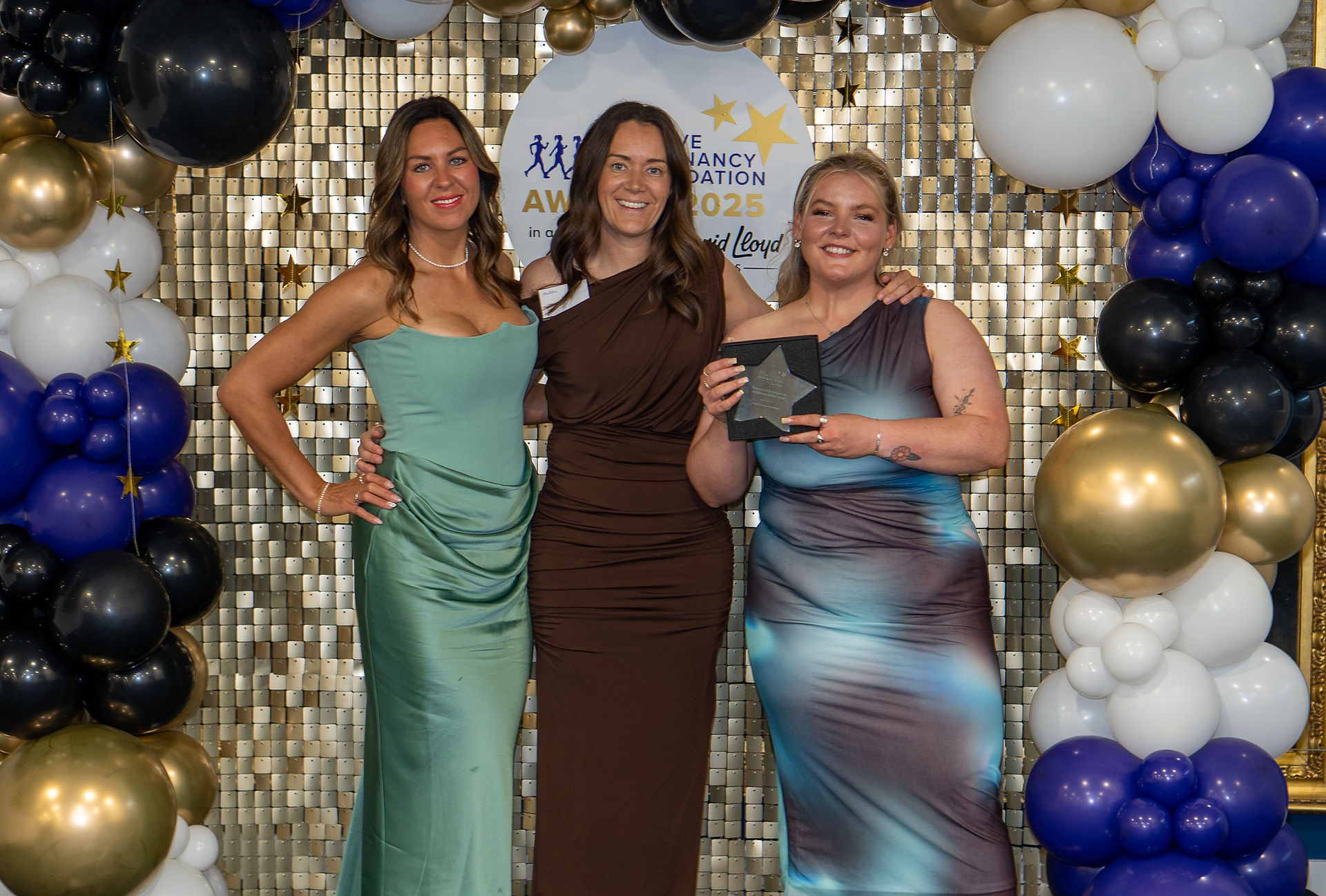 3 smiling women holding Award