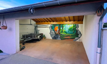 ce trompe-l'œil représente un rouge gorge posé sur un le bord d'un mur cassé au fond d'un garage, dont l'ouverture mène dans une forêt verdoyante.