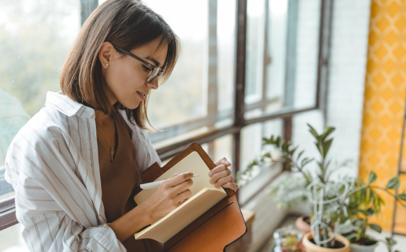 Image shows a woman writing in her diary. She is focused as she sets clear intentions for her goals.