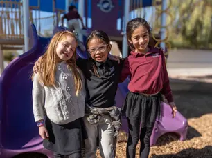 Three Capstone Christian Academy elementary students smiling on the playground in Southeast Las Vegas