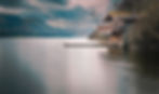 Boathouse on a calm lake with mountains in the background.