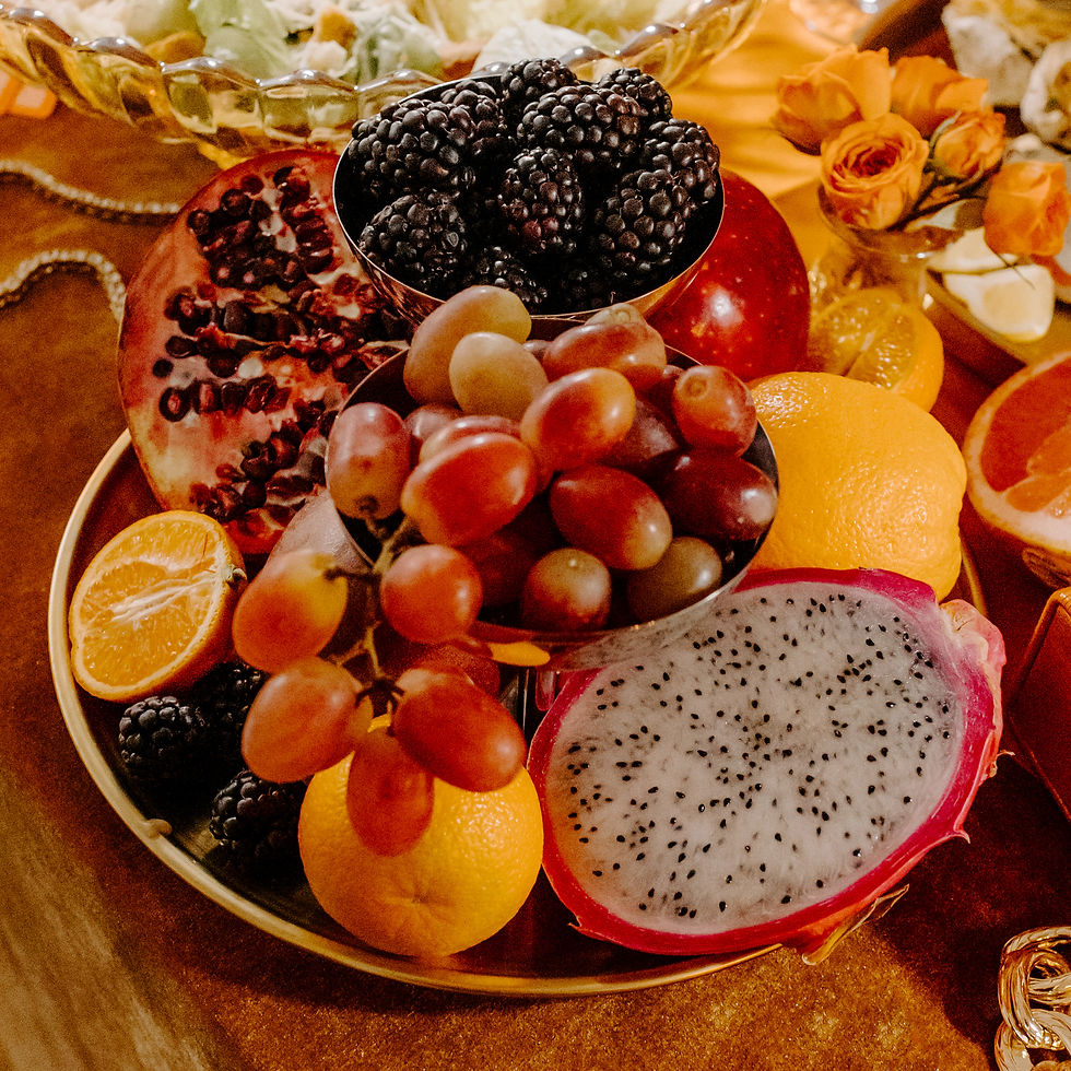 Colorful fruit platter with blackberries, red grapes, pomegranate, oranges, and dragon fruit on a warm-toned table