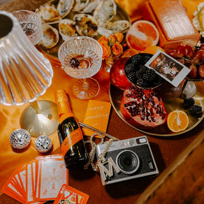Table filled with fruit, photos, champagne, cameras and mini disco balls