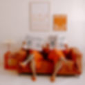 Mango Marketing Co. co-founders sitting on an orange couch reading newspapers