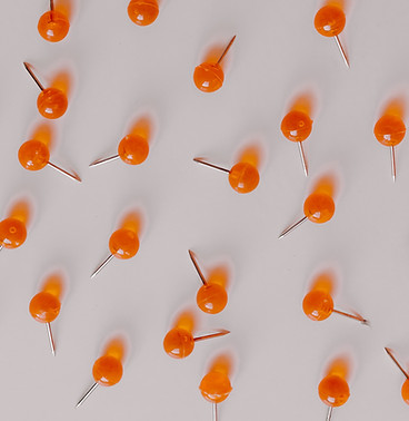 Orange push pins on white background
