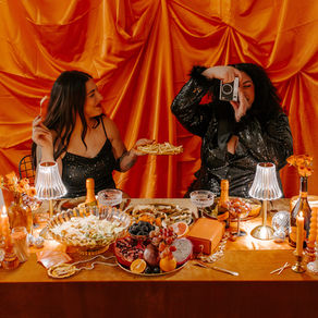Two girls eating food behind a silk background