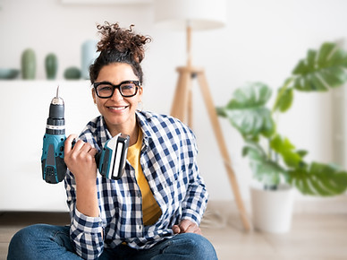 Black woman holding electric drill tool to assembly furniture in new home.jpg