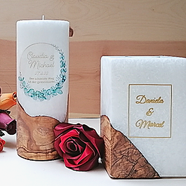 Eckige Kerze mit Ringen: Elegante rechteckige Hochzeitskerze aus Stearin mit einem Holzsockel, graviert mit Eheringen und dem Schriftzug ‚Ja‘
Zylindrische Kerze mit Baum: Runde personalisierte Hochzeitskerze mit einem eingearbeiteten Holz-Lebensbaum und den Namen des Brautpaars.
Kerze mit Kreuz: Weiße Stearinkerze mit hölzernem Kreuz-Motiv und floralen Akzenten, beleuchtet durch eine sichere LED-Kerze.
Fokus Gravur: Detailansicht einer Hochzeitskerze mit individueller Namensgravur im Holzsegment und dekorativem Band.
Größenauswahl: Verschiedene Formate und Größen der Holz-Sterin-Hochzeitskerzen in einer stilvollen Produktpräsentation.