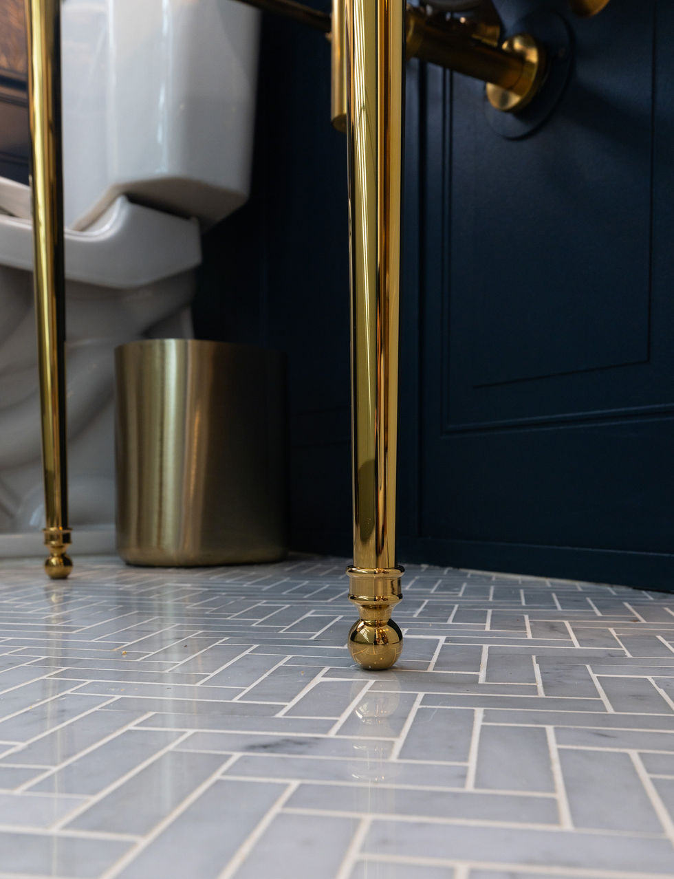 Herringbone bathroom tile floor with brass vanity leg detail in Denver remodel.