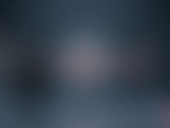 A professional conceptual image for Hristov Development showing an AI engineering partnership. Two businessmen in suits shake hands next to a glowing, structured AI neural core that connects into a stable production-ready data network. The scene uses a premium dark grey and blue color palette with subtle coral red accents, representing successful AI implementation and strategic partnership