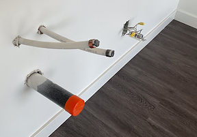 Capped plumbing lines and electrical boxes roughed in on a kitchen wall