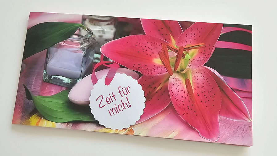Ein Geschenkgutschein, verziert mit einer wunderschönen Lilie, trägt die einladende Aufschrift "Zeit für mich".