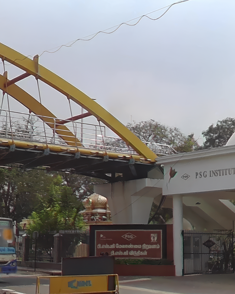 Yellow PSG Footbridge arching over a road with sign and building entrance.
