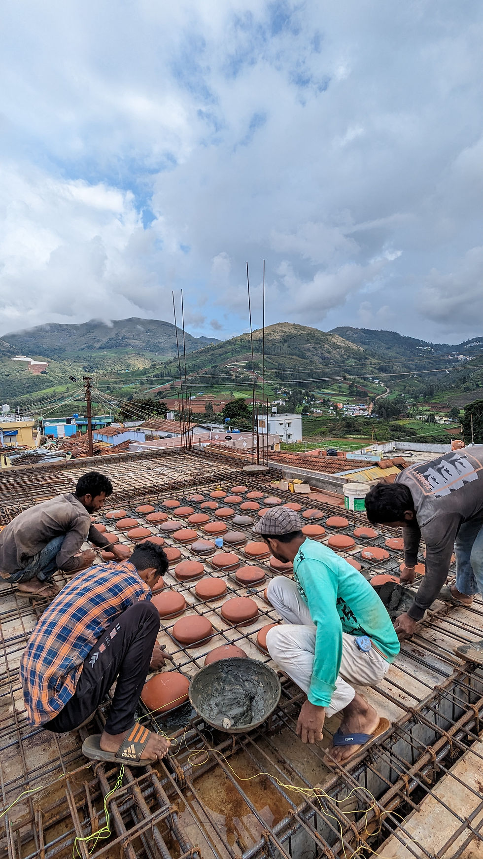 Construction workers laying terracotta pots for filler slab, sustainable construction in Kotagiri.