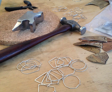 A jewelers hamer, anvil and silver earrings being shaped