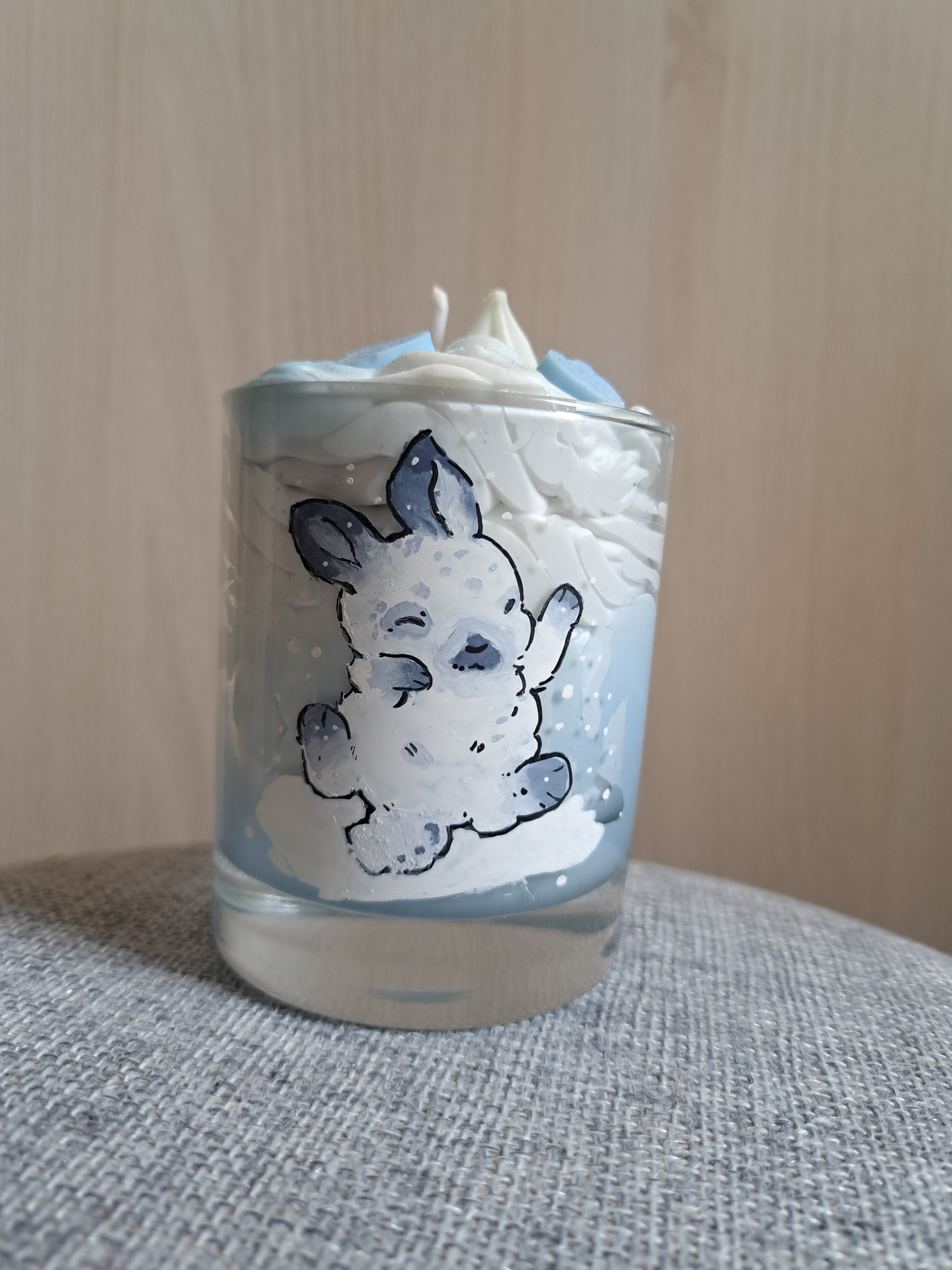 Une bougie chantilly au Monoï avec un lapin blanc et gris dessiné dessus