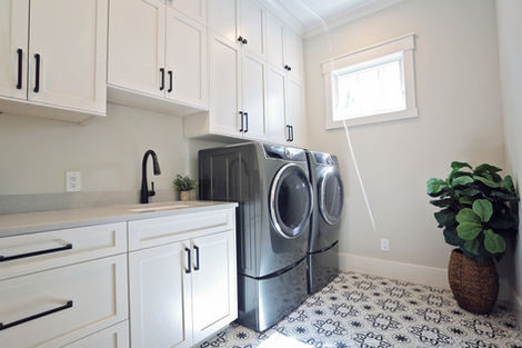 Laundry room with white cabinets, washer and dryer, and patterned floor.