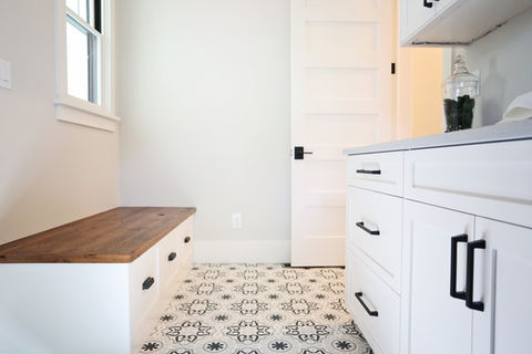 White cabinets and door with black handles in a bright laundry room.