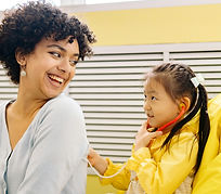Young girl examines woman with stethoscope, both smiling