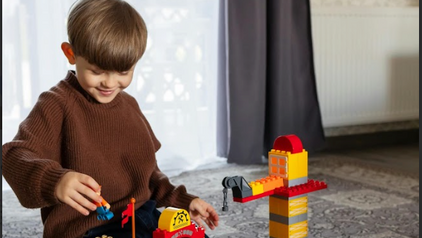 Young boy playing with blocks, constructing building structures on the floor