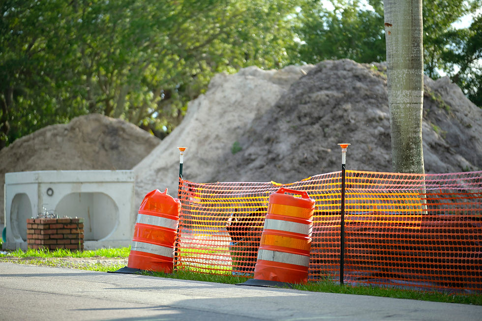 Orange safety fence and traffic barrels at a construction site