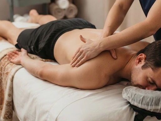 A massage therapist applying slow, sustained hands-on pressure to a client's upper back and neck, demonstrating myofascial release therapy for chronic muscle tightness.