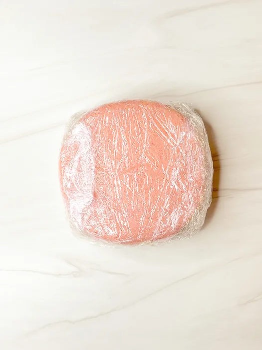 cake layer wrapped in saran wrap for freezer storage