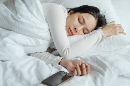 A woman sleeping with a white pillow and duvet.