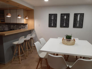 Comedor moderno con mesa, sillas y barra de cocina con taburetes.