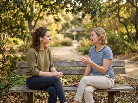 Eye-level view of two friends talking on a park bench
