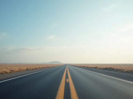 Eye-level view of a long, straight road disappearing into the horizon with a clear sky