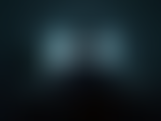 Young person sitting alone in a dimly lit room, focused on a glowing screen