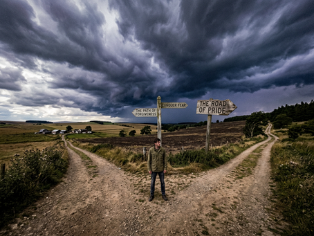 Wide-angle view of a person standing at a crossroads under stormy light.