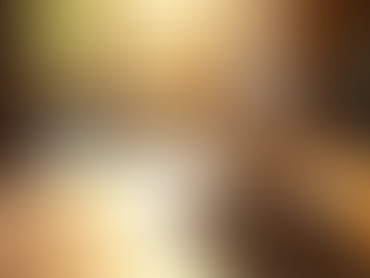 Eye-level view of a steaming cup of coffee on a wooden table with sunlight streaming through a window