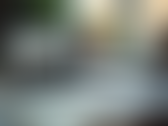 Eye-level view of a cluttered desk with scattered papers and a glowing laptop screen showing a blog post