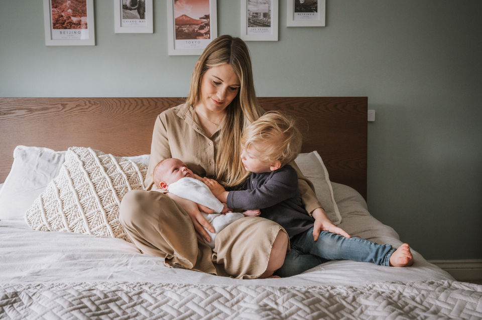 Mummy looking at her little boy gently stroking his baby brother.