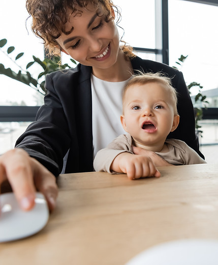 smiling-woman-working-with-baby-on-lap-at-desk-2026-01-09-12-07-34-utc.jpg