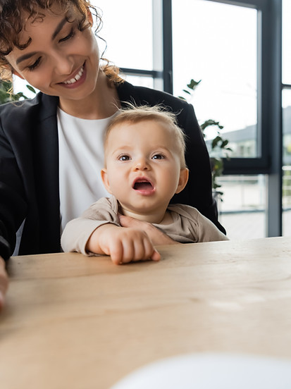 smiling-woman-working-with-baby-on-lap-at-desk-2026-01-09-12-07-34-utc.jpg