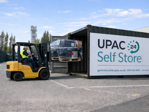 Eye-level view of a forklift loading heavy pallets into a storage container at a Glasgow self storage facility