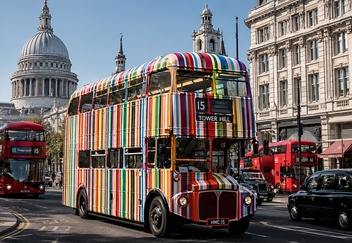 A London in central London street and the bus painted in multi-coloured vertical stripes