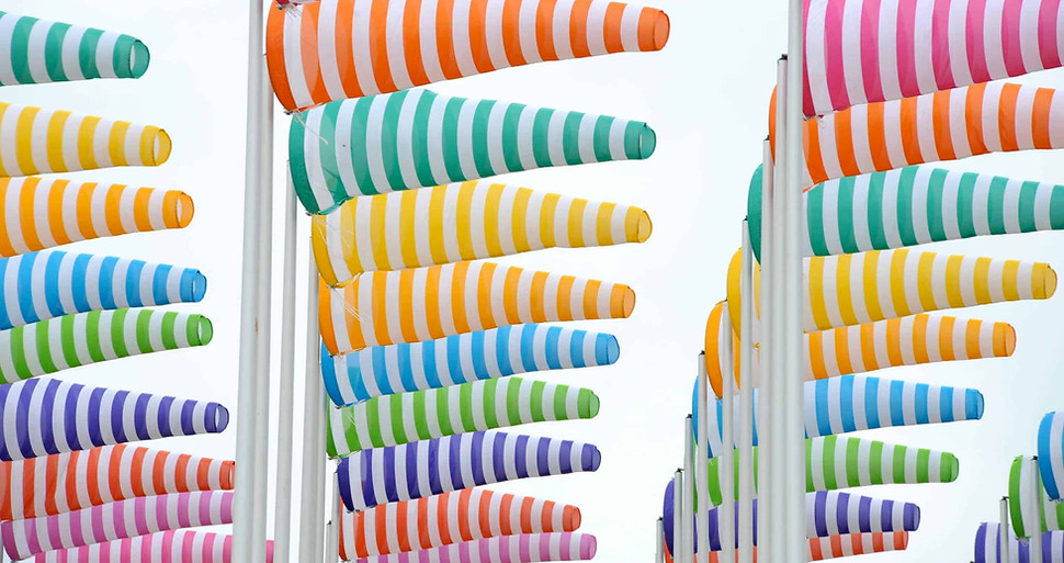 Outdoor Daniel Buren installation with vertical coloured stripes set in a landscape, illustrating his use of repeated bands of colour in relation to place, light and movement.