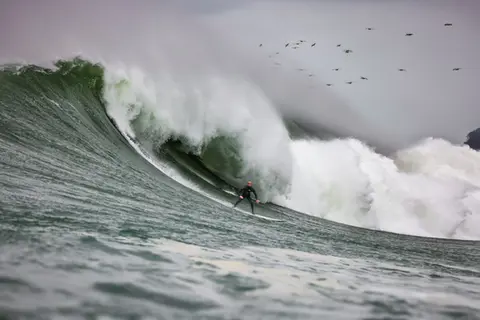 Photo of a surfer in the pipeline of a wave at Mavericks Surf Competition in Half Moon Bay, California. Photo Credit: Tom Hoppa.