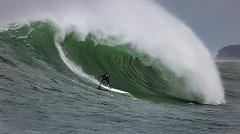 Photo of a surfer in the pipeline of a wave at Mavericks Surf Competition in Half Moon Bay, California. Photo Credit: Tom Hoppa.