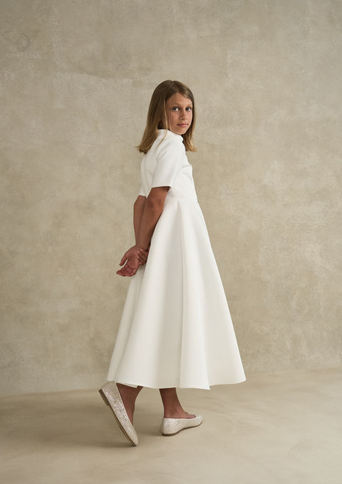 Side view of the Anne Communion dress showcasing the elegant A-line shape and smooth heavyweight matte satin fabric.