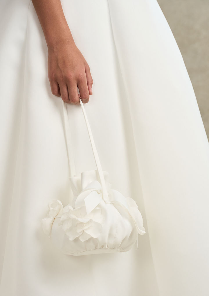 Close-up of the detachable tulle cape for the Elara Communion dress, finished with satin shoulder bows and delicate pearl embellishments.