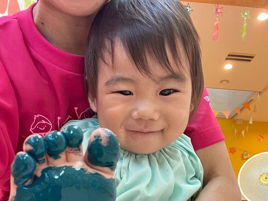 足の裏に絵具をつけた男の子