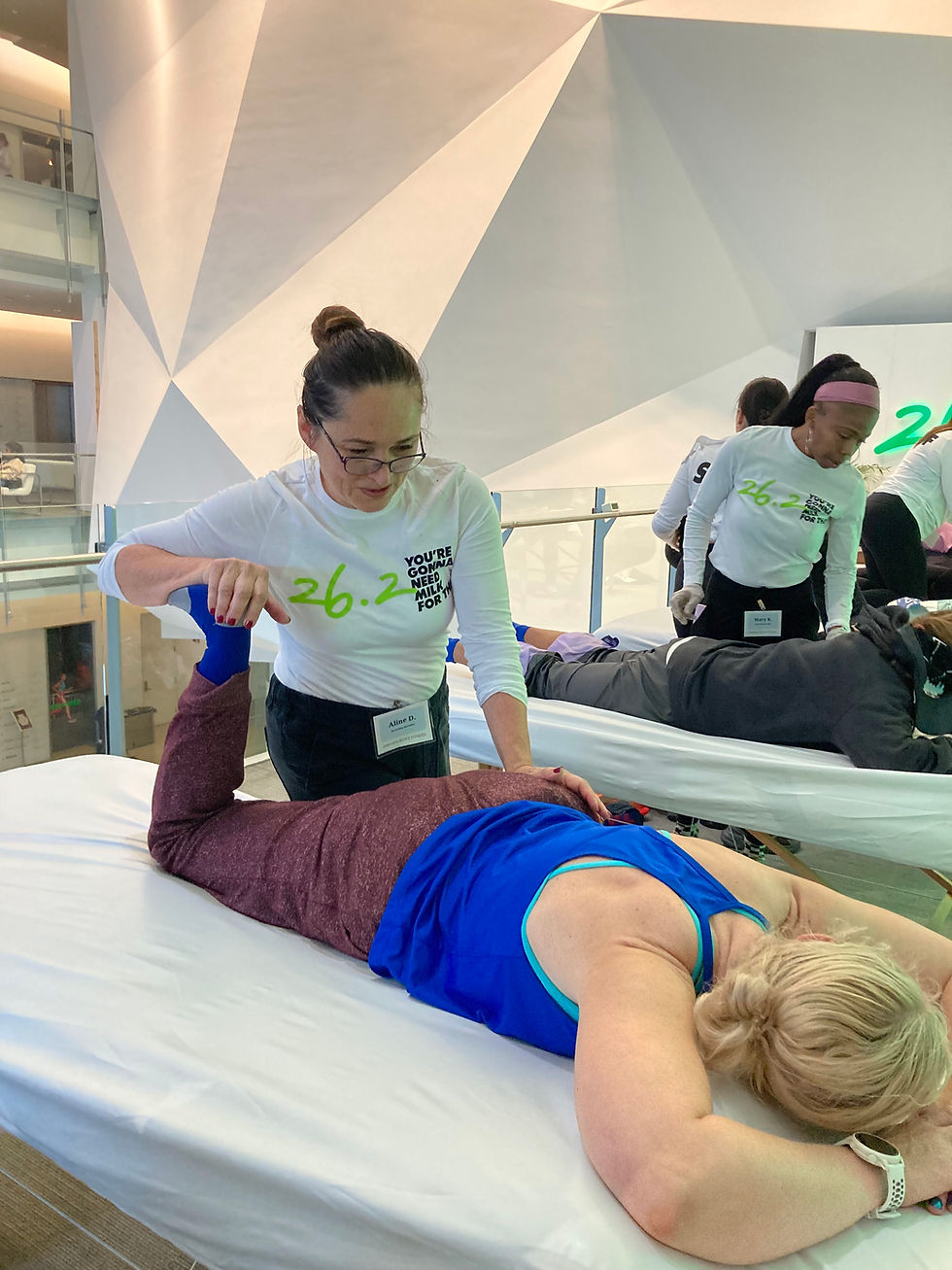 Recovery specialist, Aline Delpierre, assists a runner with lower body stretching. Stretching after running promotes blood flow and aids in recovery.