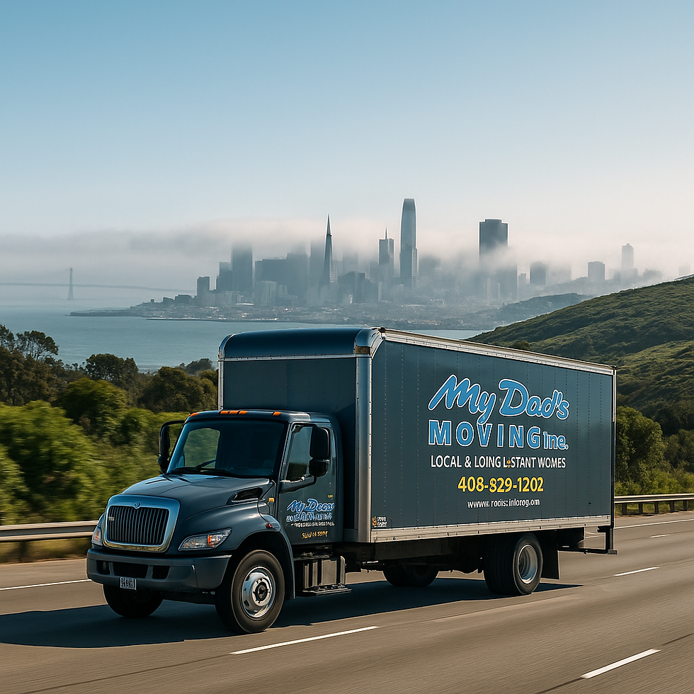 A dark gray My Dad’s Moving Inc. box truck drives on a highway flanked by green rolling hills under bright sunshine. In the distance, the San Francisco skyline rises through a low layer of fog, with the Transamerica Pyramid and Salesforce Tower faintly visible. The truck’s logo and phone number appear clearly on its side panel.