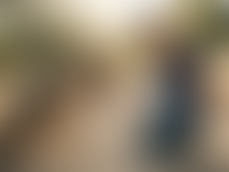 A teenage volunteer wearing a K9 4 KIDS t-shirt kneels on a dirt trail in San Martin, facilitating a calm greeting with a large rescue dog during a socialization training session.