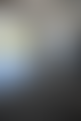 A professional technician from Heavenly Touch Stone Care, wearing a light blue company polo, cleans a glossy epoxy garage floor with a microfiber mop. Sunlight shines through open garage doors onto the reflective surface, where one side is bright and polished while the other appears slightly dull to illustrate correct versus incorrect cleaning methods.